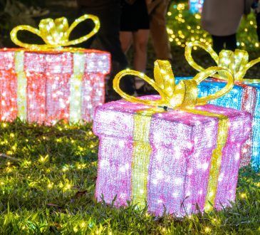 Decorated gift boxes with glowing lights on grass
