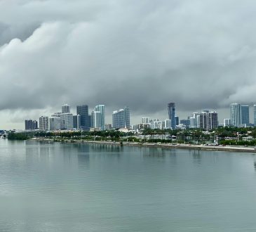 city skyline across body of water under cloudy sky during daytime