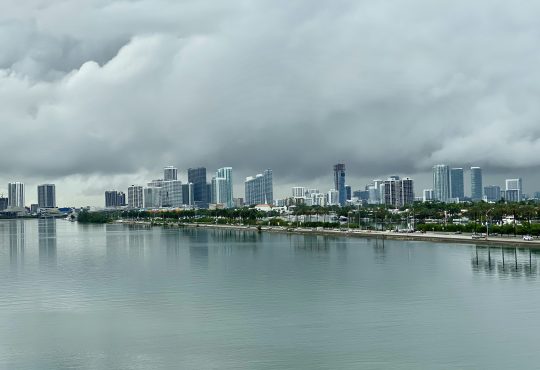 city skyline across body of water under cloudy sky during daytime